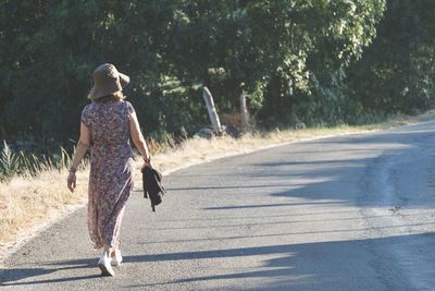 Rear view of woman walking on road