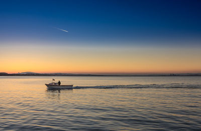 Man in boat on sea during sunset