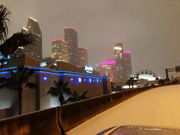 Illuminated city buildings against sky at night