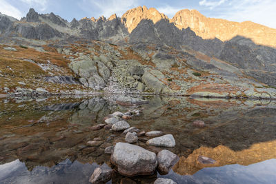 Sharp alpine peaks catching orange light and reflecting in tarn below them, slovakia, europe