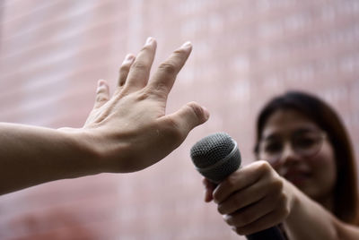 Cropped hand of person showing stop sign to female journalist