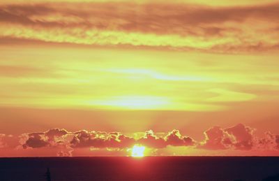 Scenic view of sea against dramatic sky during sunset