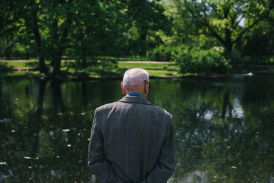 Rear view of man standing by lake