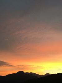 Scenic view of silhouette mountains against orange sky