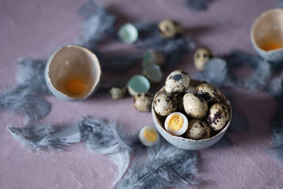 Quail eggs in ceramic vases, gray feathers on the table, easter still life,