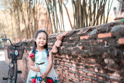 Portrait of smiling girl standing against wall