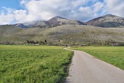 Scenic view of field and mountains against sky