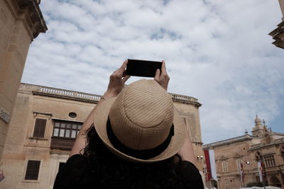 Woman photographing sky with mobile in city