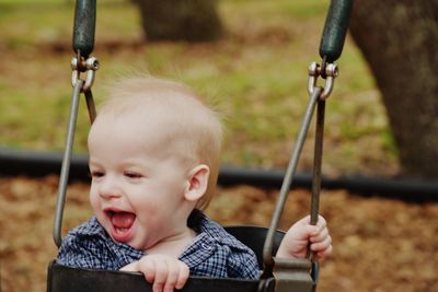 Close-up of boy sitting on swing at playground