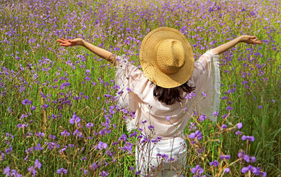 Rear view of woman standing by purple flowers on land