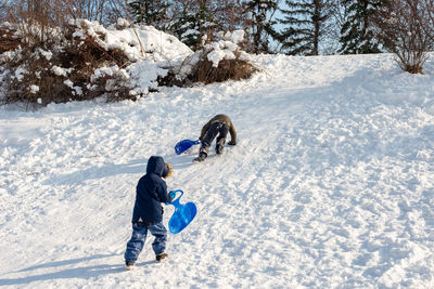 Rear view of boys playing on snow covered land