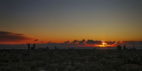 Silhouette cityscape against sky during sunset