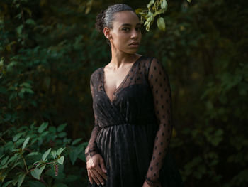 Portrait of young woman standing against plants