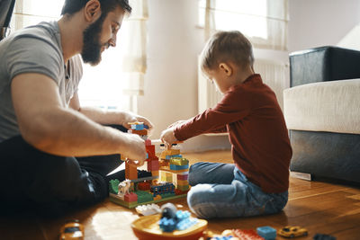 Father and son sitting on the floor playing together with building bricks