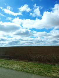 Scenic view of field against cloudy sky