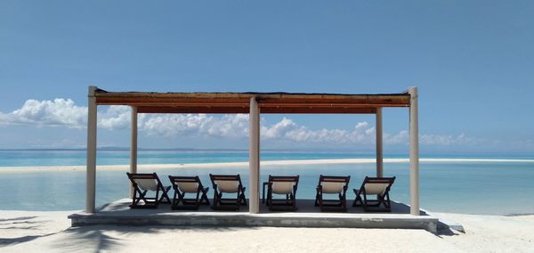 Chair on beach against clear sky