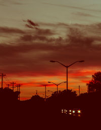 Silhouette street against orange sky