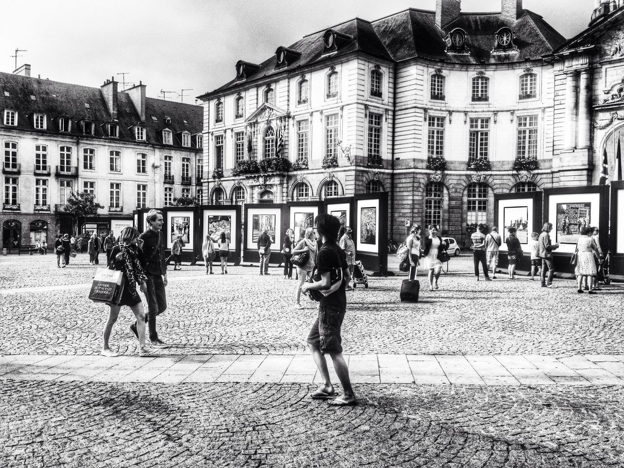 building exterior, architecture, built structure, large group of people, street, city, person, lifestyles, walking, men, city life, leisure activity, cobblestone, mixed age range, city street, building, town square, outdoors, day