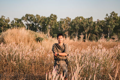 Portrait of young man standing on field against sky