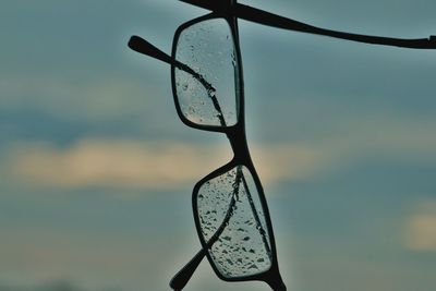 Close-up of eyeglasses against sky