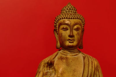 Close-up of buddha statue against red background