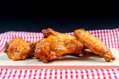 Close-up of chicken wings on cutting board against black background