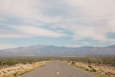 Road by mountains against sky