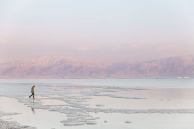 Man walking on salt formations at sunset in dead sea