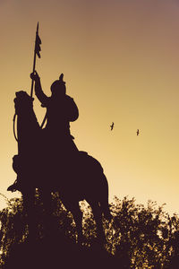 Low angle view of silhouette statue against sky during sunset