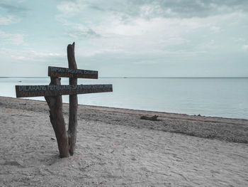 Wooden posts on beach against sky