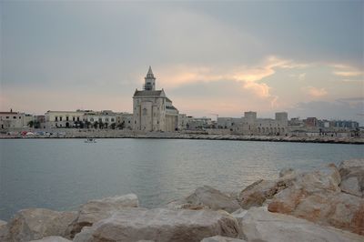 View of buildings by sea against sky