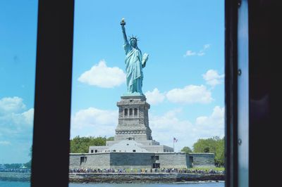 Statue of liberty against sky seen through window