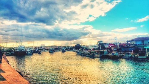 Boats moored at harbor in city against sky