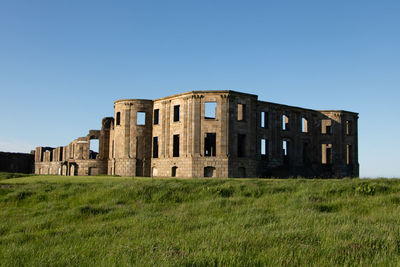 Built structure on field against clear blue sky