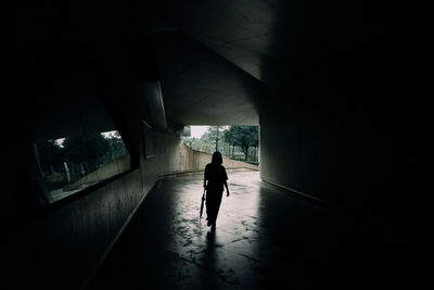 Rear view of woman walking under bridge