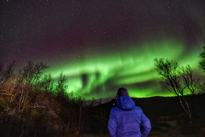 Rear view of man standing against sky at night