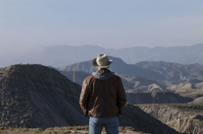 Rear view of adult man in cowboy hat looking at view of tabernas desert, almeria, spain
