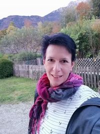 Portrait of smiling woman standing by fence during winter