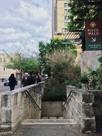 People on wall by building against sky
