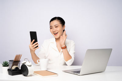 Young woman using laptop on table against white background