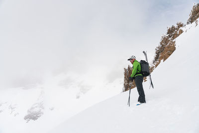 Skier standing at top of line looking out over foggy mountains