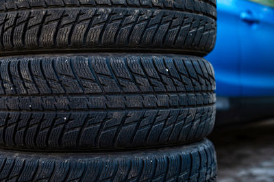 Winter tires next to the car in wheel service, seasonal tire change concept, closeup