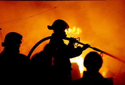 Silhouette firefighters extinguishing fire