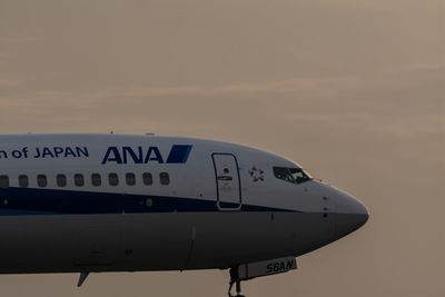 Side view of text on airplane against sky during sunset