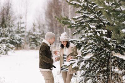 A man and a woman in love walk in a snowy forest among trees in the winter countryside in nature