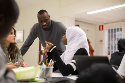 Students discussing with teacher in classroom