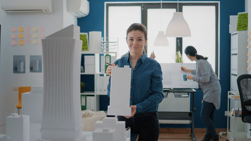 Portrait of young woman standing against building