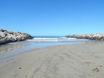 Scenic view of beach against clear blue sky