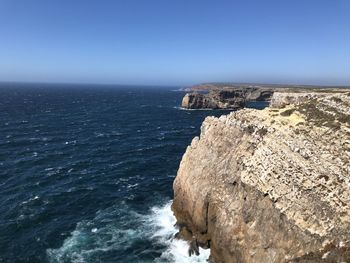 Rock formation in sea against blue sky