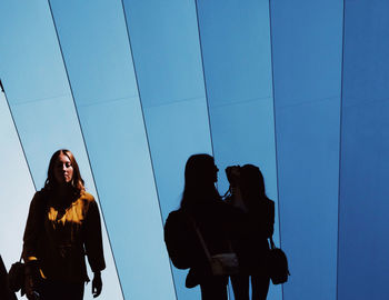 Low angle view of woman standing against blue sky